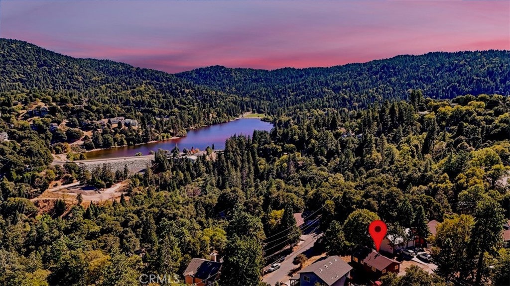 aerial view at dusk featuring a water and mountain view