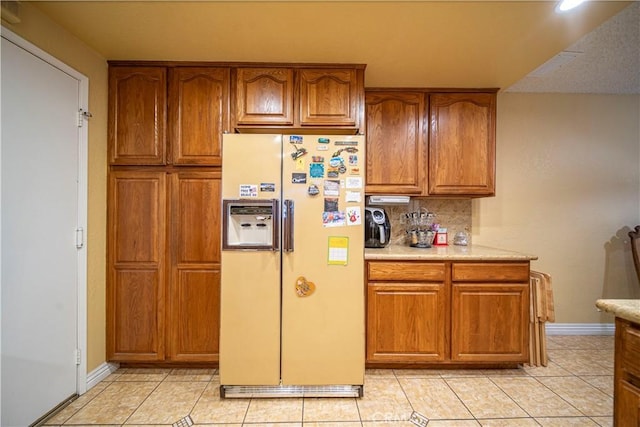 kitchen with tasteful backsplash, light tile patterned floors, and fridge with ice dispenser