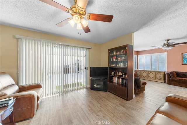 living room featuring a textured ceiling, light wood-type flooring, and a healthy amount of sunlight