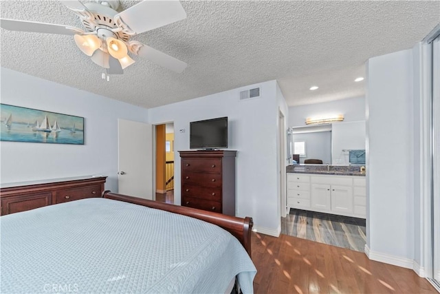 bedroom with a textured ceiling, ceiling fan, ensuite bathroom, and hardwood / wood-style flooring