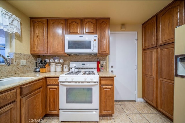 kitchen with sink, light tile patterned flooring, decorative backsplash, and white appliances