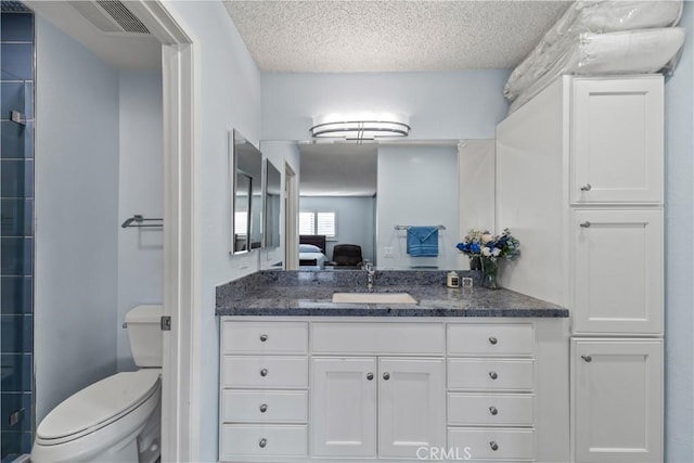 bathroom featuring a textured ceiling, toilet, a shower with door, and vanity