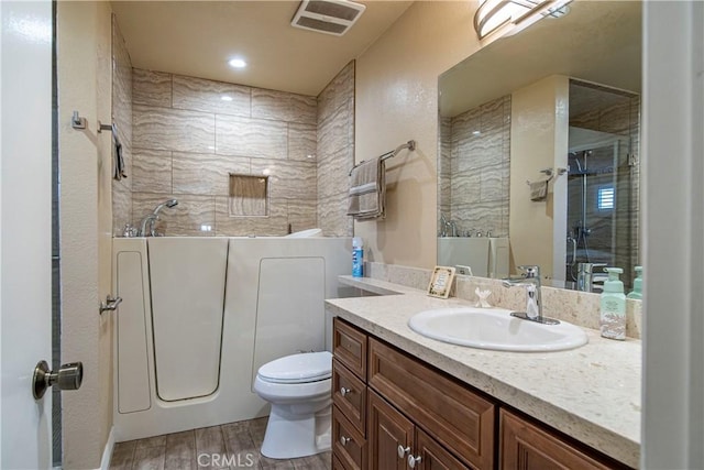 bathroom with toilet, vanity, and a shower with door