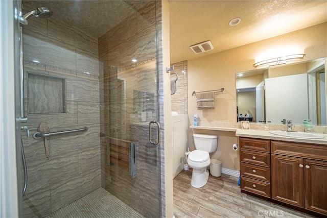 bathroom featuring a shower with shower door, toilet, and vanity