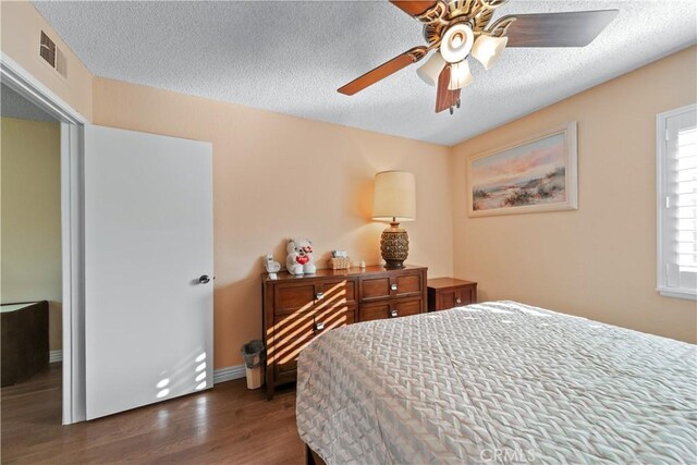 bedroom featuring a textured ceiling, ceiling fan, and dark wood-type flooring