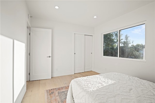 bedroom with light hardwood / wood-style floors and a closet