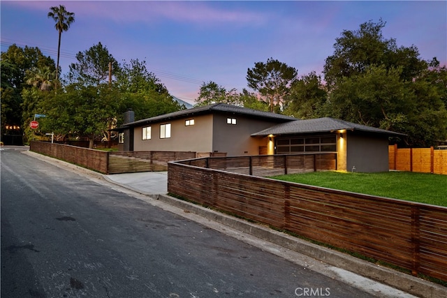 property exterior at dusk featuring a lawn