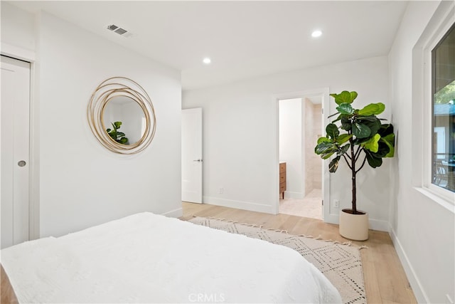 bedroom with light hardwood / wood-style floors and ensuite bath