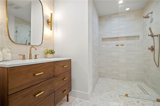 bathroom featuring vanity, a tile shower, tile patterned flooring, and tasteful backsplash