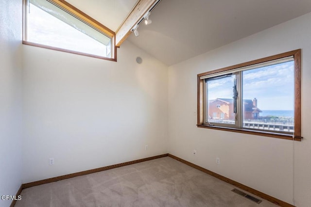 empty room with light carpet, vaulted ceiling with beams, and track lighting