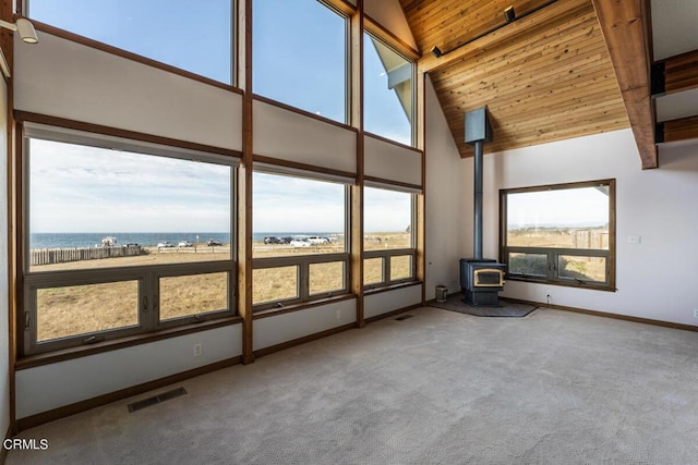 unfurnished sunroom with wood ceiling, a wood stove, a healthy amount of sunlight, and lofted ceiling