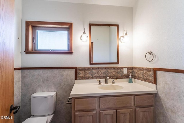 bathroom with vanity, toilet, and tile walls