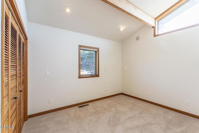 unfurnished bedroom featuring lofted ceiling with beams and light carpet