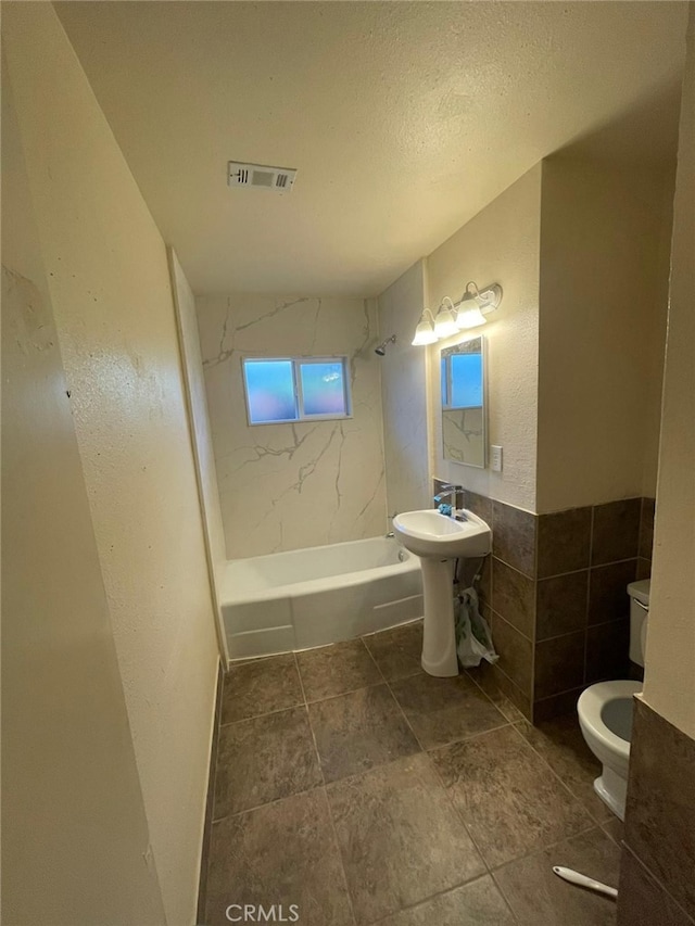 bathroom featuring tile walls, a textured ceiling, and toilet