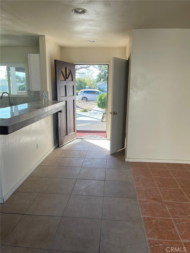 doorway featuring sink, dark tile patterned flooring, and plenty of natural light