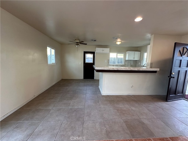 kitchen with a wall unit AC, white cabinets, kitchen peninsula, and ceiling fan