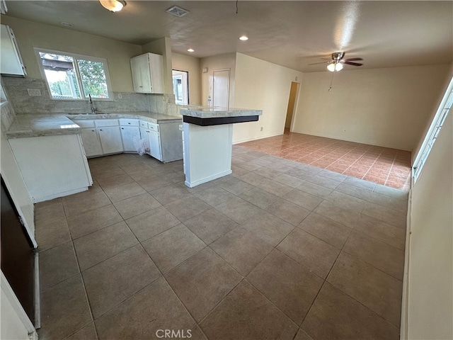 kitchen with sink, kitchen peninsula, white cabinetry, ceiling fan, and decorative backsplash