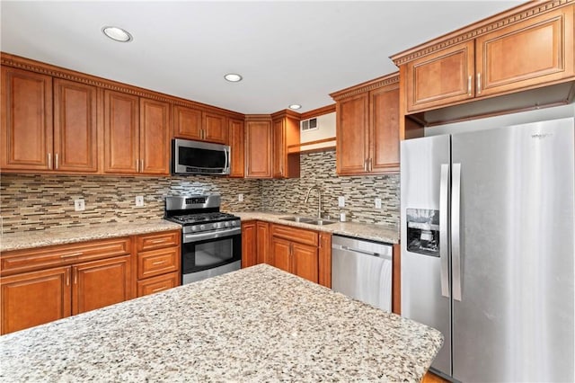 kitchen featuring tasteful backsplash, light stone counters, sink, and stainless steel appliances