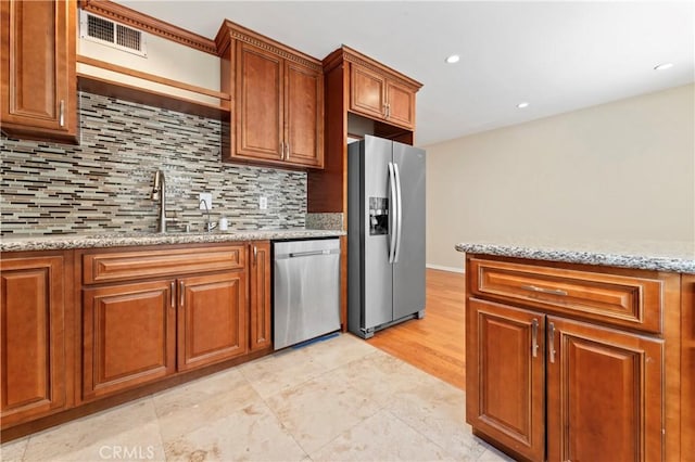 kitchen featuring backsplash, sink, light stone countertops, appliances with stainless steel finishes, and light hardwood / wood-style floors