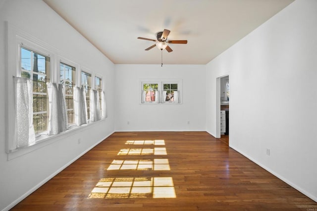 empty room with a wealth of natural light, dark hardwood / wood-style floors, and ceiling fan