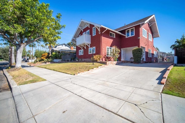 front facade with a front yard, a balcony, and a garage