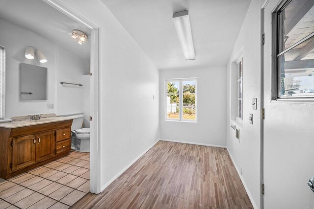 hall featuring light hardwood / wood-style flooring, sink, and vaulted ceiling