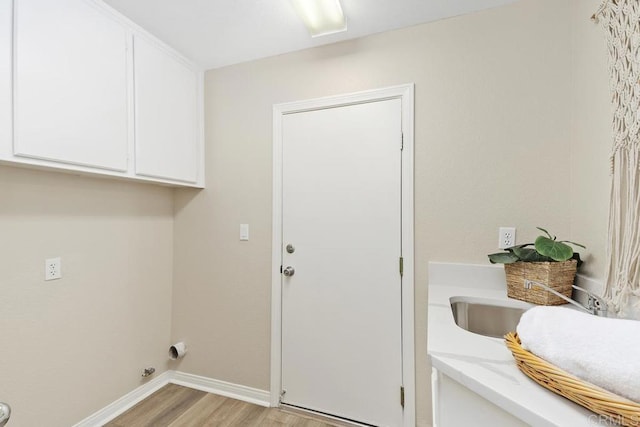 laundry area with electric dryer hookup, cabinets, and light hardwood / wood-style floors