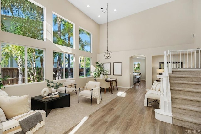 living room with hardwood / wood-style floors, a towering ceiling, and an inviting chandelier