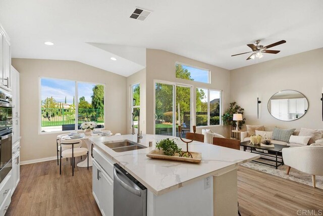 kitchen featuring white cabinets, a center island with sink, light stone countertops, light wood-type flooring, and stainless steel appliances