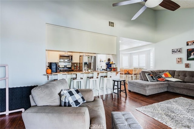 living room featuring ceiling fan and dark wood-type flooring