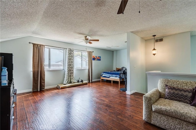 bedroom featuring ceiling fan, dark hardwood / wood-style floors, a textured ceiling, and vaulted ceiling