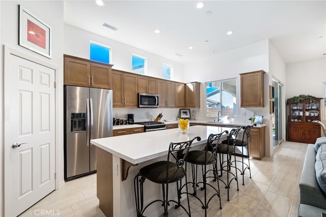 kitchen with a breakfast bar, a center island, sink, and stainless steel appliances