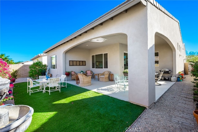 rear view of property with a lawn, an outdoor living space, and a patio