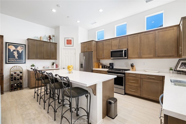 kitchen with a kitchen breakfast bar, sink, a center island, and appliances with stainless steel finishes