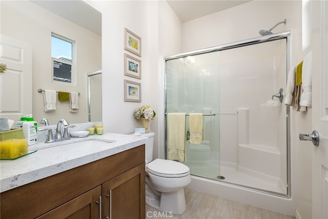 bathroom featuring toilet, vanity, and walk in shower