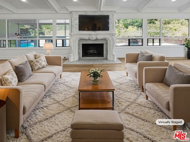 sunroom / solarium featuring a high end fireplace, a healthy amount of sunlight, and coffered ceiling