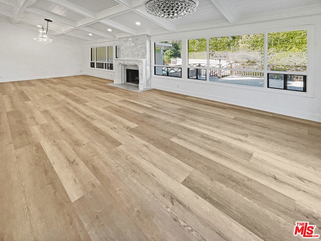 unfurnished living room with a high end fireplace, coffered ceiling, light hardwood / wood-style flooring, and a chandelier