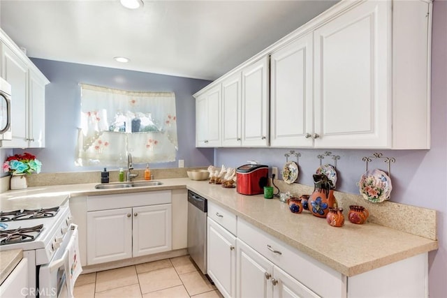 kitchen with dishwasher, white gas range oven, sink, light tile patterned flooring, and white cabinetry