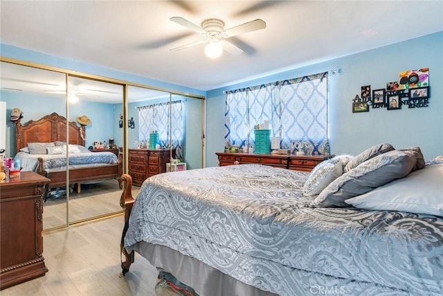 bedroom with light wood-type flooring, ceiling fan, and a closet