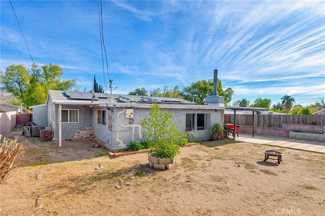 back of house featuring an outdoor fire pit and solar panels