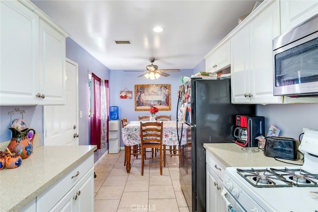 kitchen featuring ceiling fan, white cabinets, white gas range, and light tile patterned flooring