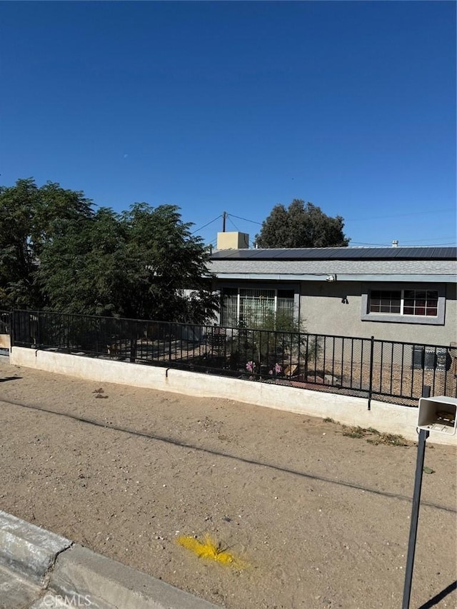 25626 Anderson Ave, Barstow, CA 92311 - view of front of home with fence, solar panels, and stucco siding