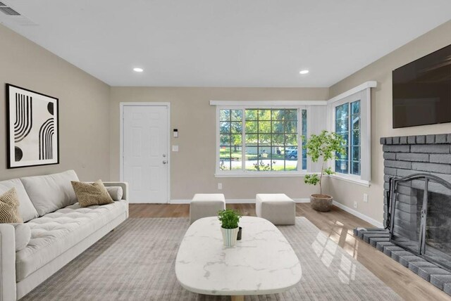 living room featuring a brick fireplace and light hardwood / wood-style floors