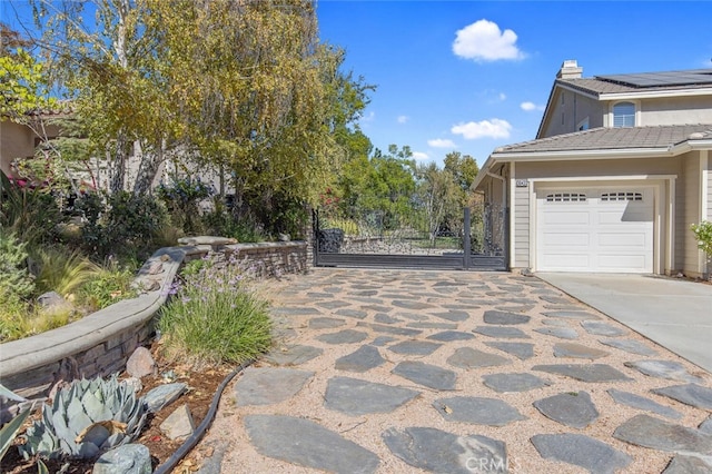 view of home's exterior with driveway, an attached garage, and a gate