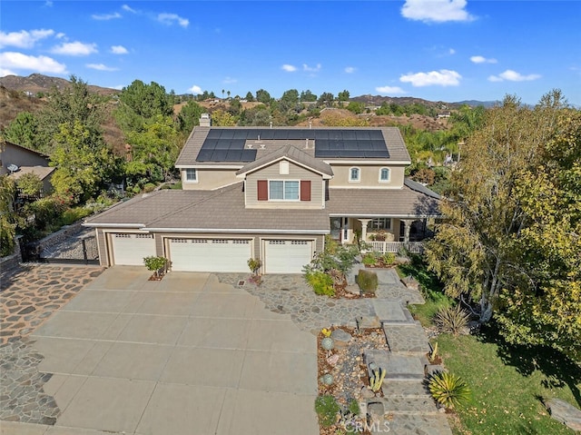 shingle-style home featuring a tile roof, a chimney, a porch, concrete driveway, and roof mounted solar panels