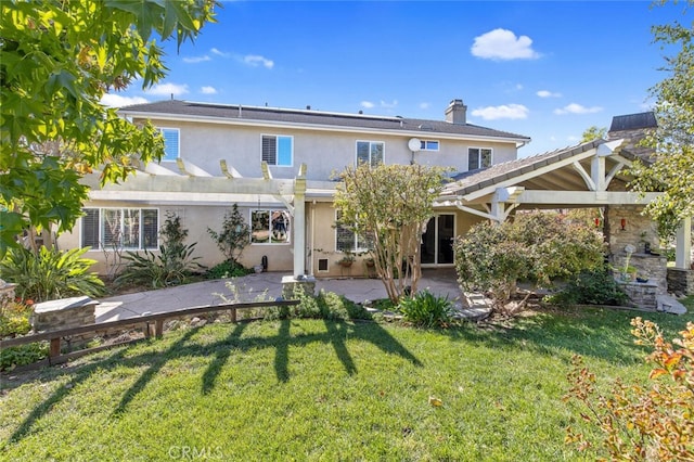 rear view of house featuring a chimney, stucco siding, a lawn, a patio area, and a pergola