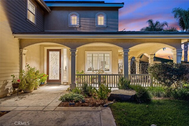 view of exterior entry featuring a porch and stucco siding