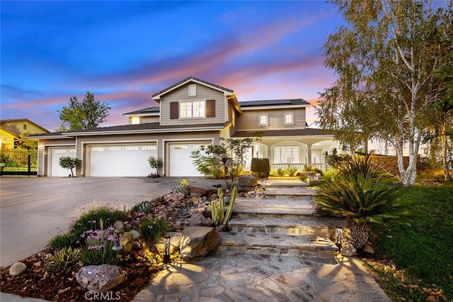 traditional-style house with a garage, solar panels, covered porch, and driveway