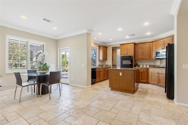 kitchen with crown molding, a wealth of natural light, a center island, and black appliances