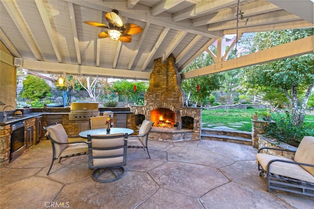 view of patio / terrace with an outdoor stone fireplace, ceiling fan, exterior kitchen, sink, and grilling area